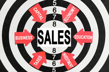 On the target, arrows with business lettering point to the center on a business card with the inscription - SALES
