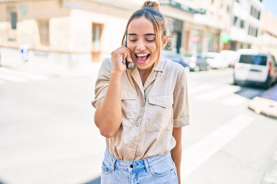Young beautiful blonde caucasian woman smiling happy outdoors on a sunny day using smartphone