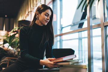 Smiling woman taking books in library