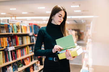 Young woman choosing book in bookshop