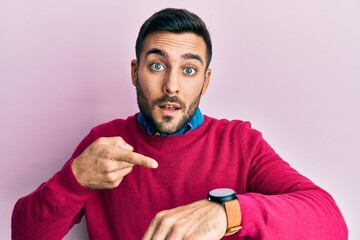 Young hispanic man wearing casual clothes in hurry pointing to watch time, impatience, upset and angry for deadline delay