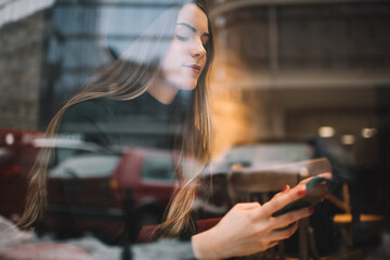 Calm stylish young woman using smartphone in cafe
