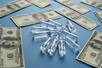 Glass vials with vaccine and dollars on blue background