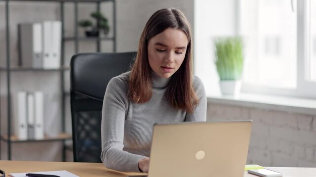 Young girl working with laptop sitting in home office. Texting messages, browsing internet, searching information, studying online. Online education, remote working, courses online