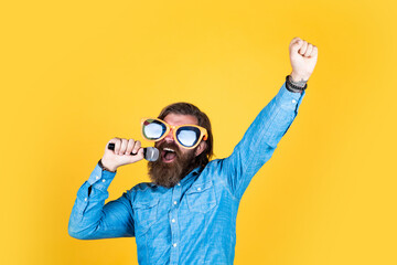 winner. celebrate the holiday. hipster singing a song. music. happy bearded man wear funny party glasses. mature event manager hold microphone. have some fun. birthday party singer