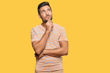 Handsome hispanic man wearing casual clothes with hand on chin thinking about question, pensive...