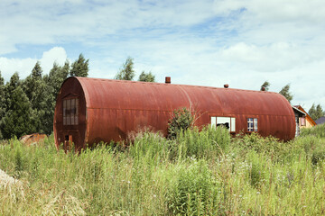 House from an old rusty cistern overgrown with grass around