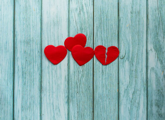 Different combination of red hearts: single, double and broken heart located on wooden planks. Background for Valentine's day.