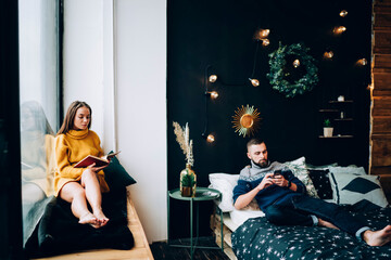 Couple wearing warm clothes relaxing in decorated bedroom