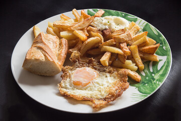 Presentation of fried egg with bread and chips on an elegant plate. Traditional food and recipes.
