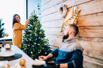 Sweet couple decorating fir tree and sitting at festive table