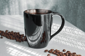 Hot coffee in a cup, against the background of openwork shadows from the window and scattered...