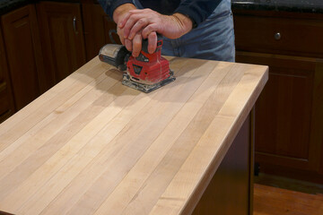 Using an electric sander to refinish a counter top