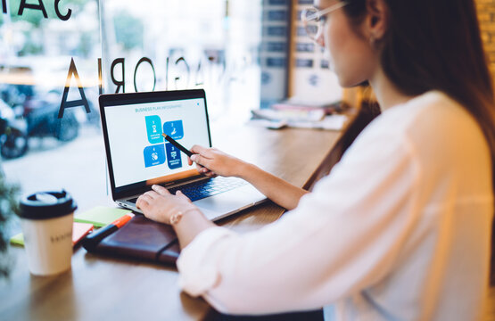 Cropped image on caucasian female student in casual wear using laptop computer for learning online course, rear view of businesswoman checking graphic chart of trade on web page on remote job