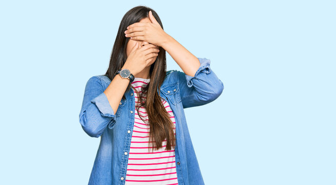 Young brunette woman wearing casual clothes covering eyes and mouth with hands, surprised and shocked. hiding emotion