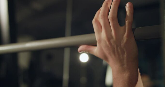 Male person lying under barbell bar and catching it for training in a gym