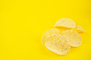 Yellow potato chips with salt and season on a yellow background