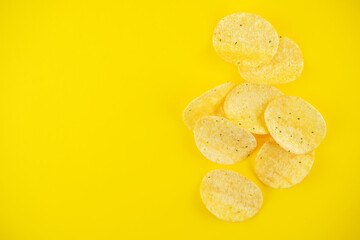Yellow potato chips with salt and season on a yellow background