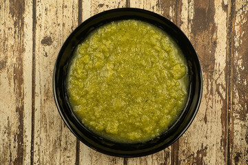 a black plate of fresh vegetable green cream soup served on rustic background