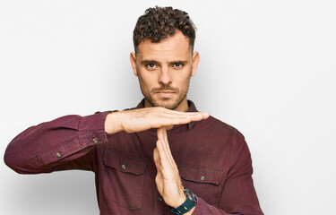Young hispanic man wearing casual clothes doing time out gesture with hands, frustrated and serious...