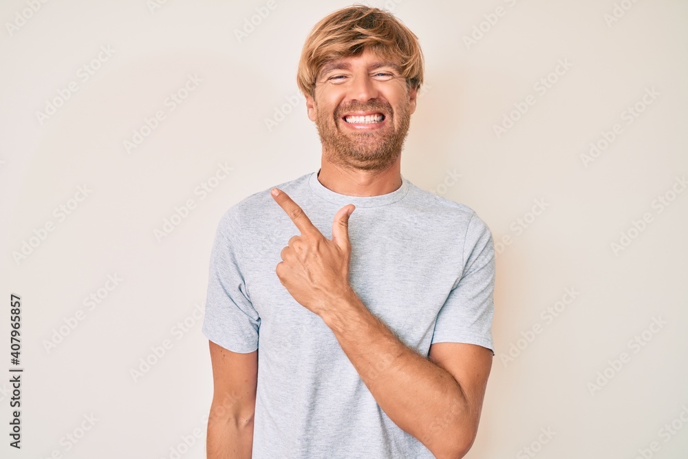 Poster young blond man wearing casual clothes cheerful with a smile of face pointing with hand and finger u