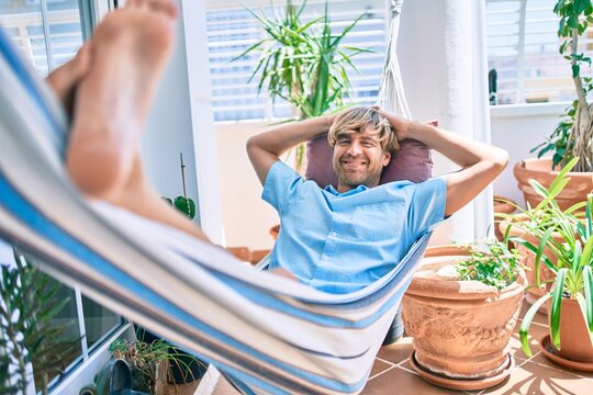 Middle age handsome man at the terrace of his house relaxing lying on a hammock