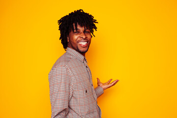 young handsome african american guy student posing cheerful and gesturing on yellow background, lifestyle people concept