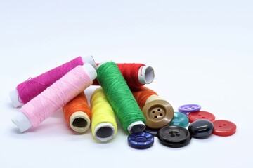Colored cotton threads and buttons on a white background.