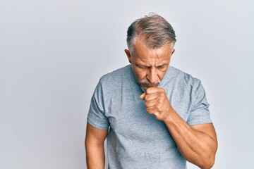 Middle age grey-haired man wearing casual clothes feeling unwell and coughing as symptom for cold...