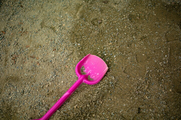 abandoned children's plastic spatula in stones and sand