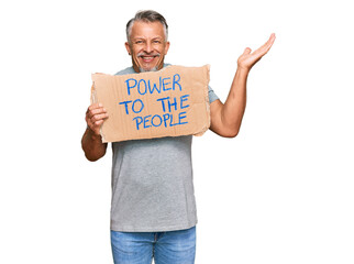 Middle age grey-haired man holding power to the people banner celebrating victory with happy smile and winner expression with raised hands
