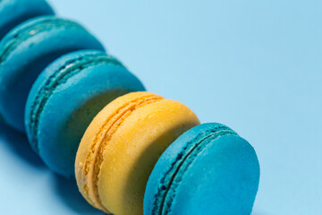 One yellow macaroon in the middle of other blue macaroons.