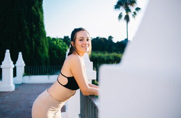 Delighted young ethnic lady resting on villa terrace after yoga training