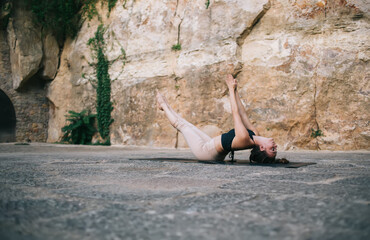 Slim woman doing Flying Fish posture lying on sports mat