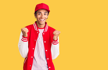 Young african amercian man wearing baseball uniform celebrating surprised and amazed for success with arms raised and open eyes. winner concept.