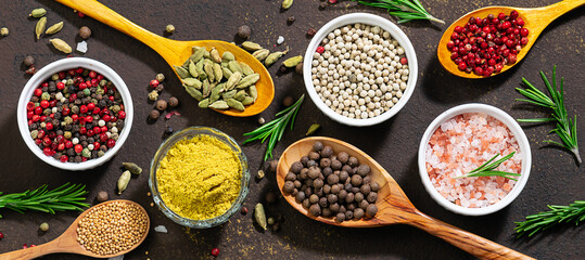 Long wide banner with assortment of organic aromatic spices and herbs on dark stone background top view. Healthy food ingredients concept.