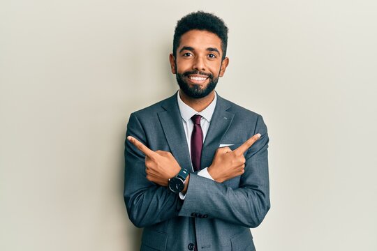Handsome hispanic man with beard wearing business suit and tie pointing to both sides with fingers, different direction disagree