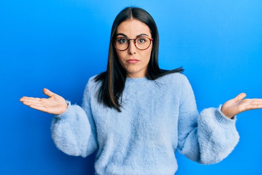 Young brunette woman wearing casual clothes and glasses clueless and confused with open arms, no idea and doubtful face.