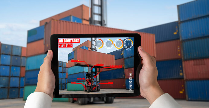 Engineer use augmented reality software in cargo container yard with automated application . Futuristic machinery in working in concept of Industry 4.0 or 4th industrial revolution.