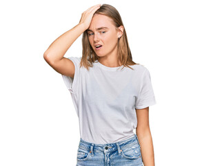 Obraz premium Beautiful young blonde woman wearing casual white t shirt surprised with hand on head for mistake, remember error. forgot, bad memory concept.