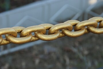 long of a big yellow iron chain in a fence outside on gray background