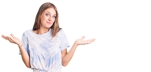 Young beautiful blonde woman wearing tye die tshirt clueless and confused expression with arms and...