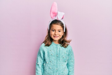 Little beautiful girl wearing cute easter bunny ears with a happy and cool smile on face. lucky person.