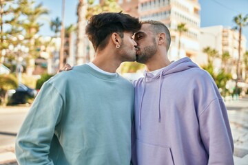 Young gay couple hugging and kissing at the city.