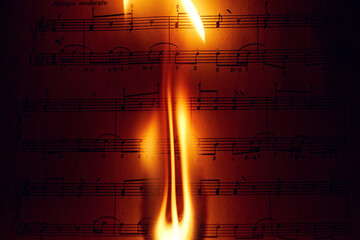 Close-up of a flame on a sheet of music.