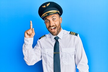 Handsome man with beard wearing airplane pilot uniform pointing finger up with successful idea. exited and happy. number one. © Krakenimages.com