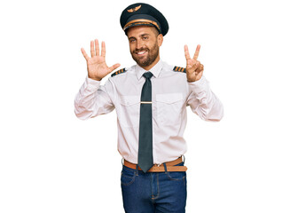 Handsome man with beard wearing airplane pilot uniform showing and pointing up with fingers number seven while smiling confident and happy.