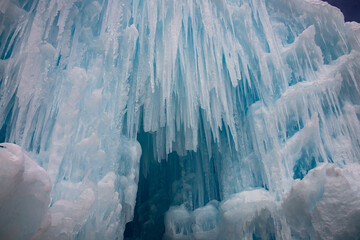 A walkway through ice. Blue and white icicles are hanging from above and the pathway is covered in snow.