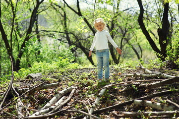 Naklejka na ściany i meble Little child girl playing in the spring forest.