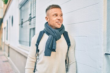 Young caucasian man smiling happy wearing backpack at the city.